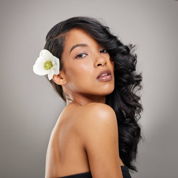 My hair is the crown I wear on a daily. a beautiful young woman posing with a flower in her hair - Photo, image