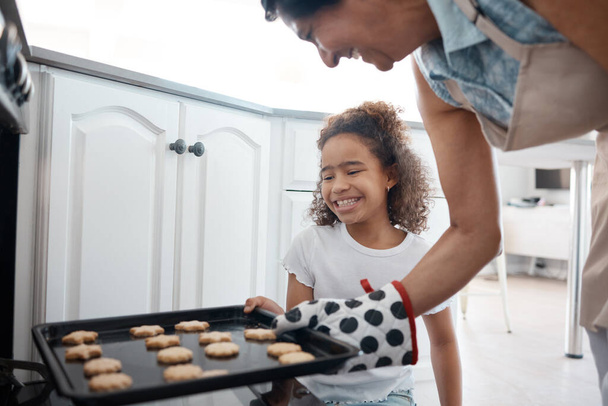 Marrone dorato proprio come piacciono a me. una donna matura che inserisce un vassoio di biscotti che ha cotto con sua nipote in un forno - Foto, immagini