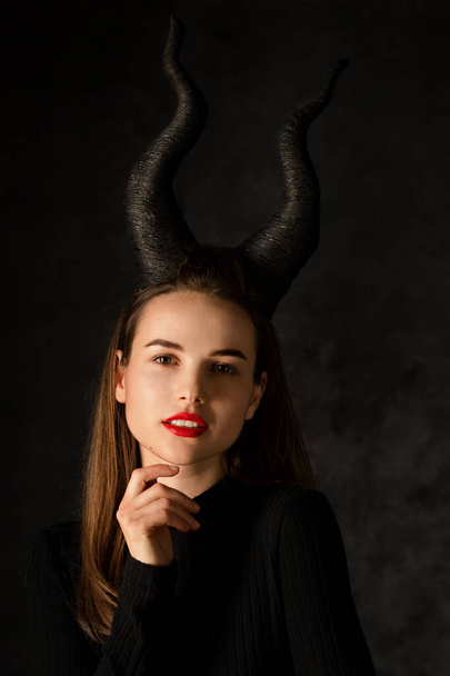 Young beautiful woman with long horns on a black background - Φωτογραφία, εικόνα