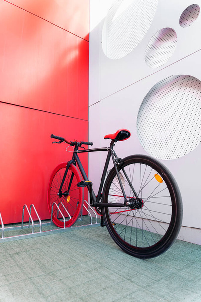 Όμορφο κόκκινο ποδήλατο σταθμευμένο στην πόλη σε ειδικό χώρο στάθμευσης για ποδήλατα. - Φωτογραφία, εικόνα