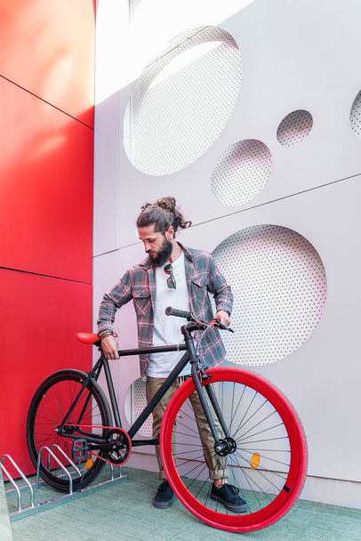 Bearded man with long hair parking his cool red bike in the city. - 写真・画像