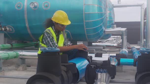 Young woman engineer examining pipeline and looking digital tablet with professional in the factory, mechanic or technician inspector plumber valve, one person, industrial and maintenance concept. - Materiaali, video