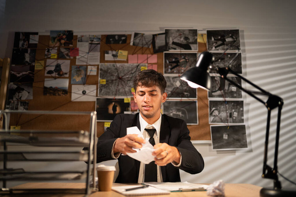 Mérges frusztrált nyomozó dolgozik az íróasztalnál az irodájában, és összegyűri a papírt a munkahelyéről, érzelmeiről és kudarcáról - Fotó, kép