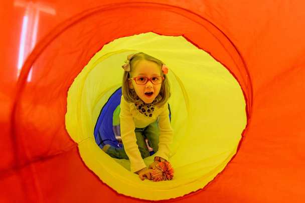 Girl living with cerebral palsy playing in sensory room, snoezelen, during therapy session. People with cerebral palsy can have problems swallowing and commonly have eye muscle imbalance. They also might have reduced range of motion at various joints - 写真・画像