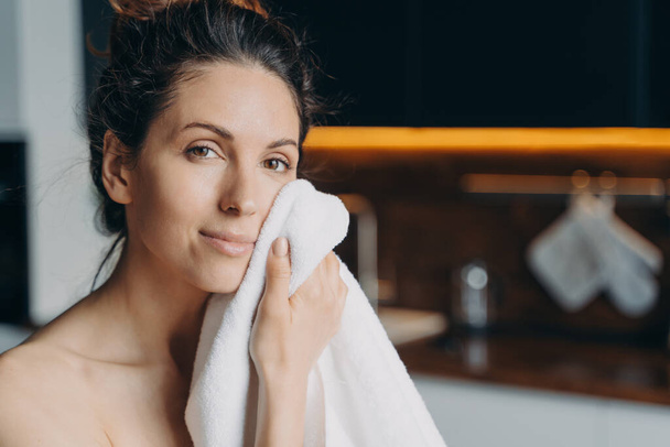 Pretty young latina woman wipe rub face with towel after shower, female do morning beauty procedures enjoying healthy smooth skin at home looking at camera. Hygiene, skincare concept. - Photo, Image