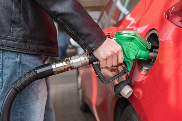 Man is pumping gas in red car in fuel station. - Фото, зображення