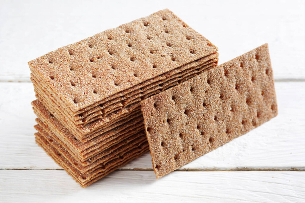 Hromada žitného křupavého chleba na bílém dřevěném pozadí - Fotografie, Obrázek