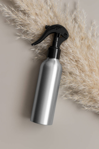 Aluminium cosmetic trigger sprayer bottle  mockup with a pampas on the beige background. - Photo, Image