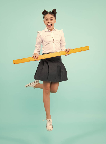 Teenager child school girl holding measure for geometry lesson. Measuring height. Measuring equipment. Kid student study math. Happy positive and smiling schoolgirl - Zdjęcie, obraz