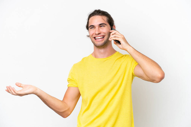 Blanke knappe man geïsoleerd op witte achtergrond houden van een gesprek met de mobiele telefoon met iemand - Foto, afbeelding