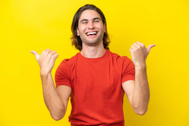 Blanke knappe man geïsoleerd op gele achtergrond met duimen omhoog gebaar en glimlach - Foto, afbeelding
