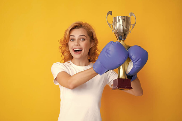 Cheerful woman celebrating victory. Woman in boxing gloves hold champion winner cup - Foto, immagini