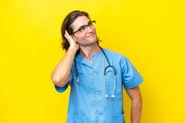 Young surgeon caucasian man isolated on yellow background thinking an idea - Photo, Image