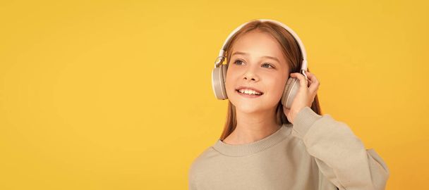 Muziekliefhebber. Luister naar muziek. accessoire voor draadloze headsets. Kinderportret met koptelefoon, horizontale poster. Meisje dat naar muziek luistert, banner met kopieerruimte - Foto, afbeelding