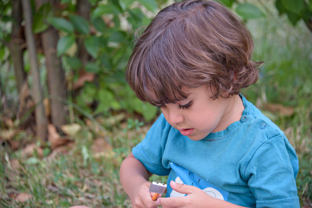 公園の屋外で学校の宿題をしている若い白人の学校の少年。子供は鉛筆を外に置いてノートに書く。自己教育学専攻。子供のための早期開発 - 写真・画像