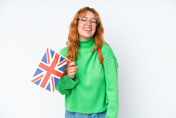 Jovem caucasiana segurando uma bandeira do Reino Unido isolada em fundo branco rindo - Foto, Imagem