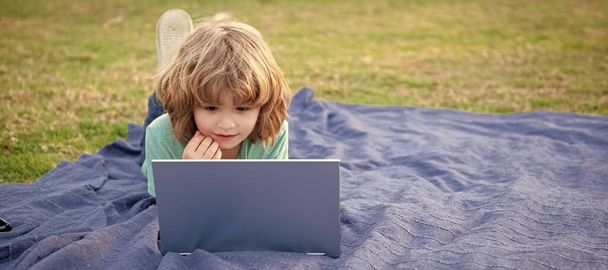 Jongen kind gebruik laptop computer learning technologie ontspannen op deken natuurlijke buitenlucht, online cursussen. Horizontaal posterontwerp. Web banner header, kopieer ruimte - Foto, afbeelding