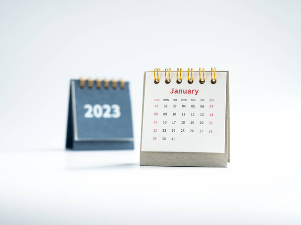 2023年1月主催者のカレンダーデスクは、白い背景を計画し、思い出させる。青いカバーの近くに白い小さなテーブルのカレンダージャン月のページ2023年の数字、幸せな新年。新しく始めろ. - 写真・画像