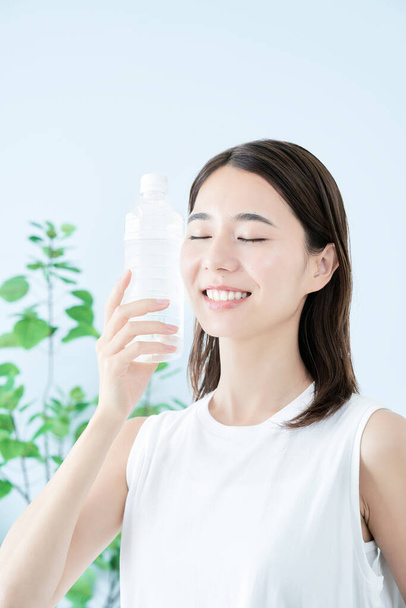 Νεαρή γυναίκα πίνει νερό από πλαστικό μπουκάλι - Φωτογραφία, εικόνα