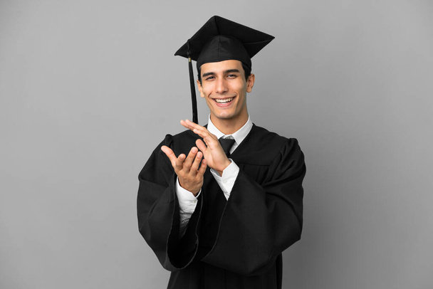 Νεαρός Αργεντινός απόφοιτος πανεπιστημίου απομονωμένος σε γκρίζο φόντο χειροκροτώντας μετά από παρουσίαση σε συνέδριο - Φωτογραφία, εικόνα