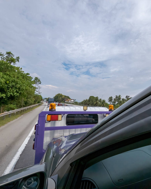 Perak, Malaysia - Aug 7, 2022 : Tow truck with broken car on the road. View from behind. - Fotografie, Obrázek