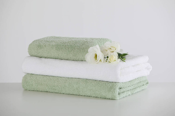 Soft folded towels with eustoma flowers on white table - Foto, Imagem