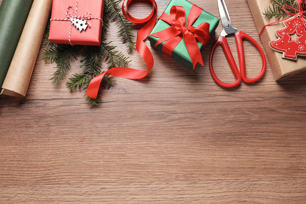 Επίπεδη σύνθεση lay με όμορφα κουτιά δώρων Χριστουγέννων και χαρτί περιτυλίγματος σε ξύλινο τραπέζι. Χώρος για κείμενο - Φωτογραφία, εικόνα
