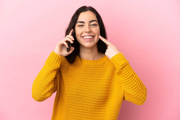 Young caucasian woman using mobile phone isolated on pink background giving a thumbs up gesture - Foto, Bild
