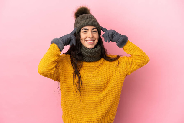 Νεαρό καυκάσιο κορίτσι με χειμερινό καπέλο απομονωμένο σε μωβ φόντο έχοντας αμφιβολίες και σκέψη - Φωτογραφία, εικόνα
