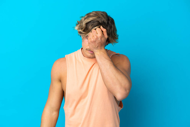 Handsome blonde man isolated on blue background with headache - Foto, afbeelding