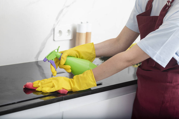 Primer plano de las manos femeninas sosteniendo spray de botella y trapo para limpiar la estufa - Foto, Imagen