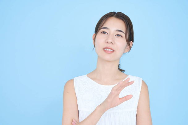 Aziatisch jong vrouw spreken en blauw achtergrond - Foto, afbeelding