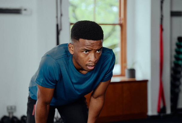 Focused young black man in sportswear taking a break between workout at the gym - 写真・画像