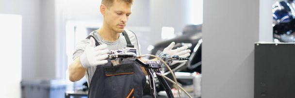 Un hombre repara el volante de una motocicleta. Centro de servicio del club de motos, reparación de bicicletas en el garaje - Foto, imagen