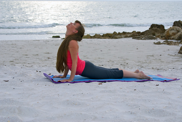 Mulher fazendo ioga exercício para cima enfrentando cão pose na praia ao sol
 - Foto, Imagem