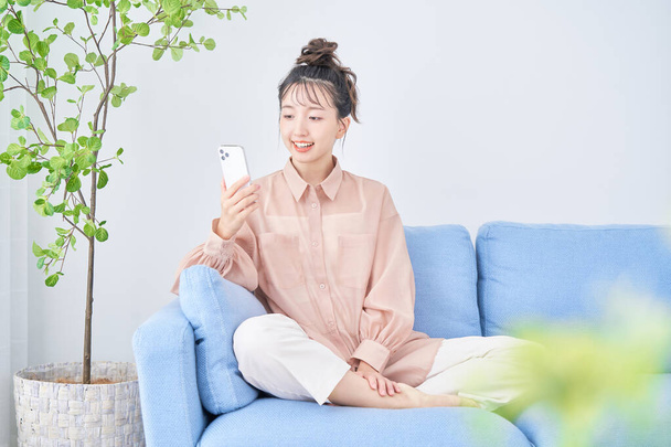 Asian young woman using smartphone in the room - Zdjęcie, obraz