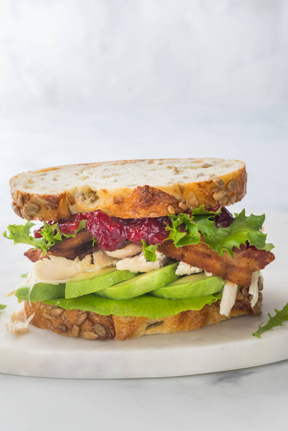 Close up em linha reta em vista de um sanduíche de peru e bacon clube com molho de cranberry e abacate.  - Foto, Imagem
