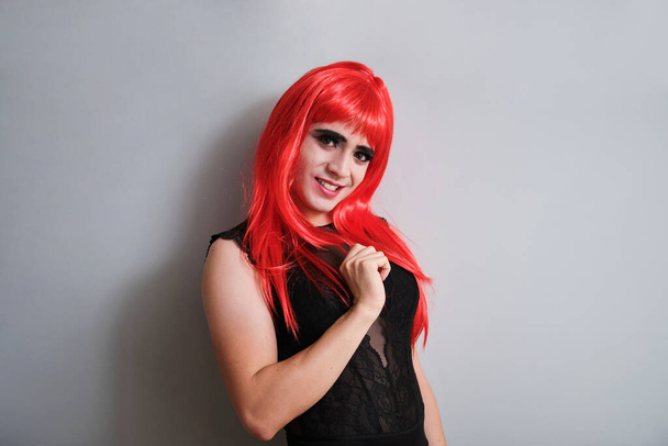 Porträt einer lächelnden Drag Queen mit roter Perücke auf grauem Hintergrund. LGBTQ queer. - Foto, Bild