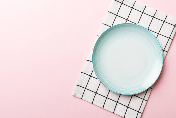 Visão superior sobre fundo colorido vazio redondo Placa azul na toalha de mesa para alimentos. Prato vazio no guardanapo com espaço para o seu design. - Foto, Imagem