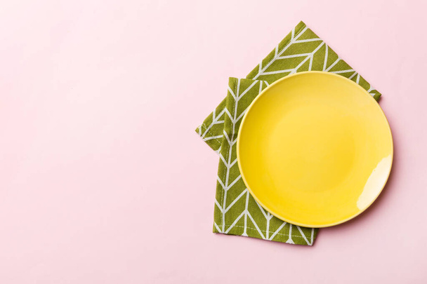 Top view on colored background empty round yellow plate on tablecloth for food. Empty dish on napkin with space for your design. - Photo, Image