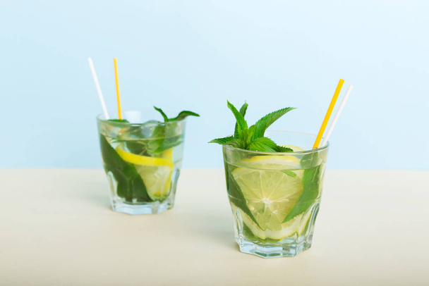 Mojito zomer verfrissende cocktail met ijs en munt. mojito cocktail met limoen, citroen en munt in een groot glas met een stok. - Foto, afbeelding