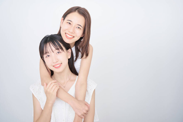 Dos mujeres sin mangas blancas posando en la foto - Foto, Imagen