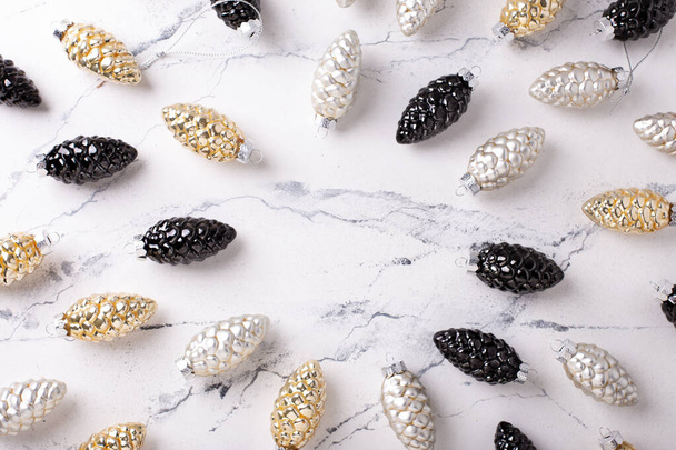 Flat lay with  Christmas decorations. Glass gold, black, silver decorative cones on grey textured background. Scandinavian minimalistic style. Still life. Top view. - Photo, image