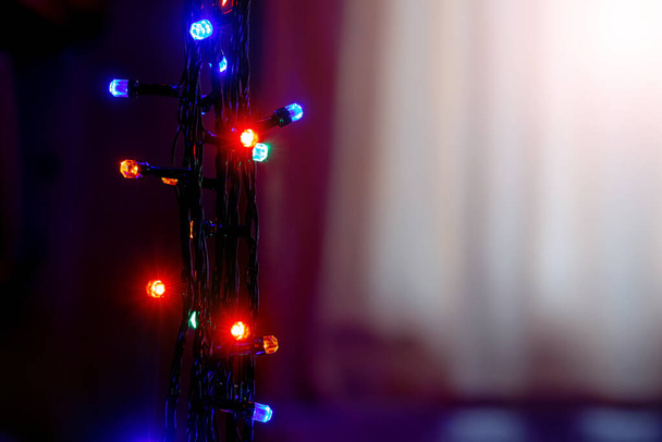 Navidad festiva y Año Nuevo con luces coloridas guirnalda sobre fondo negro cerca de la ventana, espacio de copia - Foto, Imagen