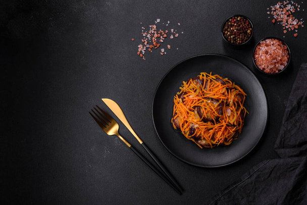 Korean salad with carrots and aubergine in a plate with garlic, black textured background - Photo, Image