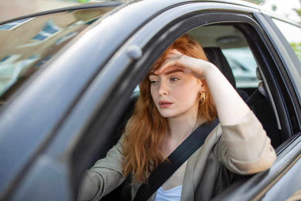 Nervous female driver sits at wheel, has worried expression as afraids to drive car by herself for first time. Frightened woman has car accident on road. People, driving, problems with transport - Photo, Image