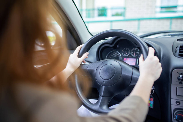 Krásná usmívající se mladá zrzka žena za volantem řízení auta. - Fotografie, Obrázek