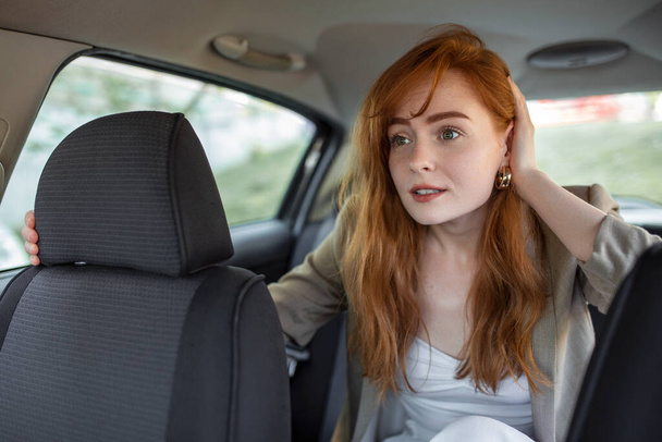 налякана жінка тримає руку на голові під час їзди в машині на розмитому передньому плані
 - Фото, зображення