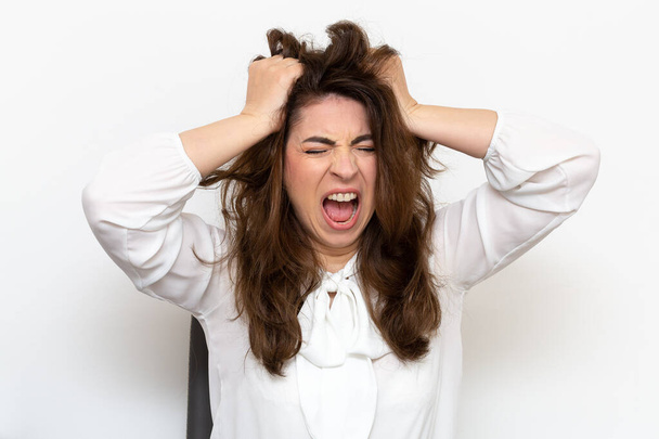 Scene of anger and hysterism of an employee who has a nervous crisis. Woman screaming and tears her hair from despair - Foto, imagen