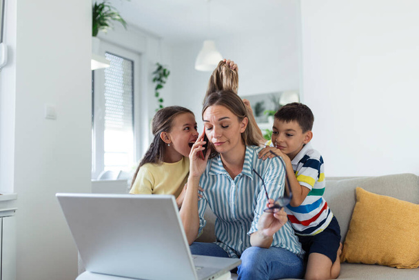 Upset mother having problem with noisy naughty daughter and son jumping on couch and screaming, demanding attention, frustrated mum tired of difficult child trying to work from home - Photo, Image